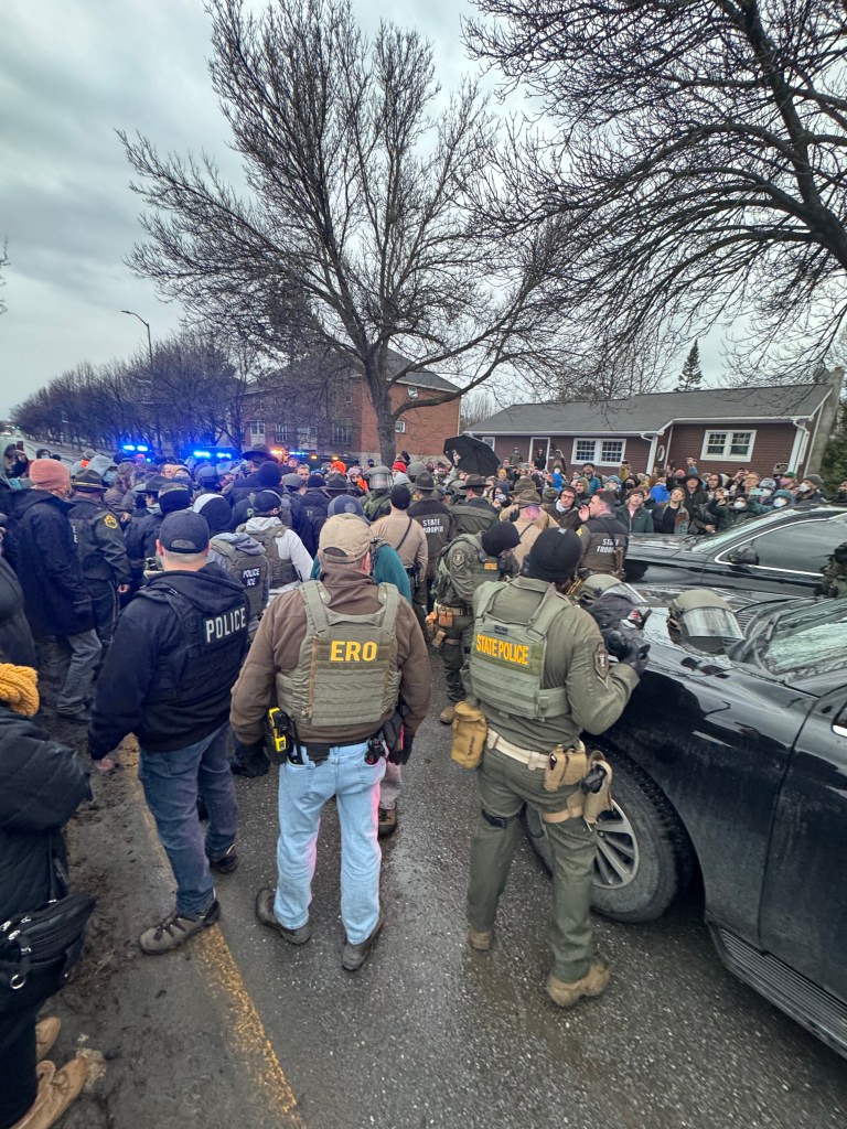 Officers stand in the streets next to vehicles 